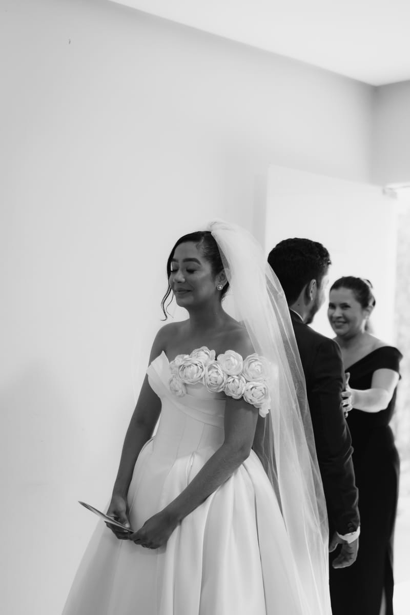 Fotografia em preto e branco da noiva com o noivo e Weiri Borges ao fundo.